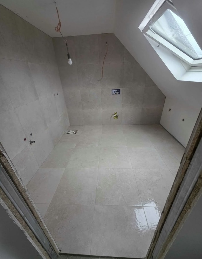 Salle de bain sous combles avec carrelage beige et vasque